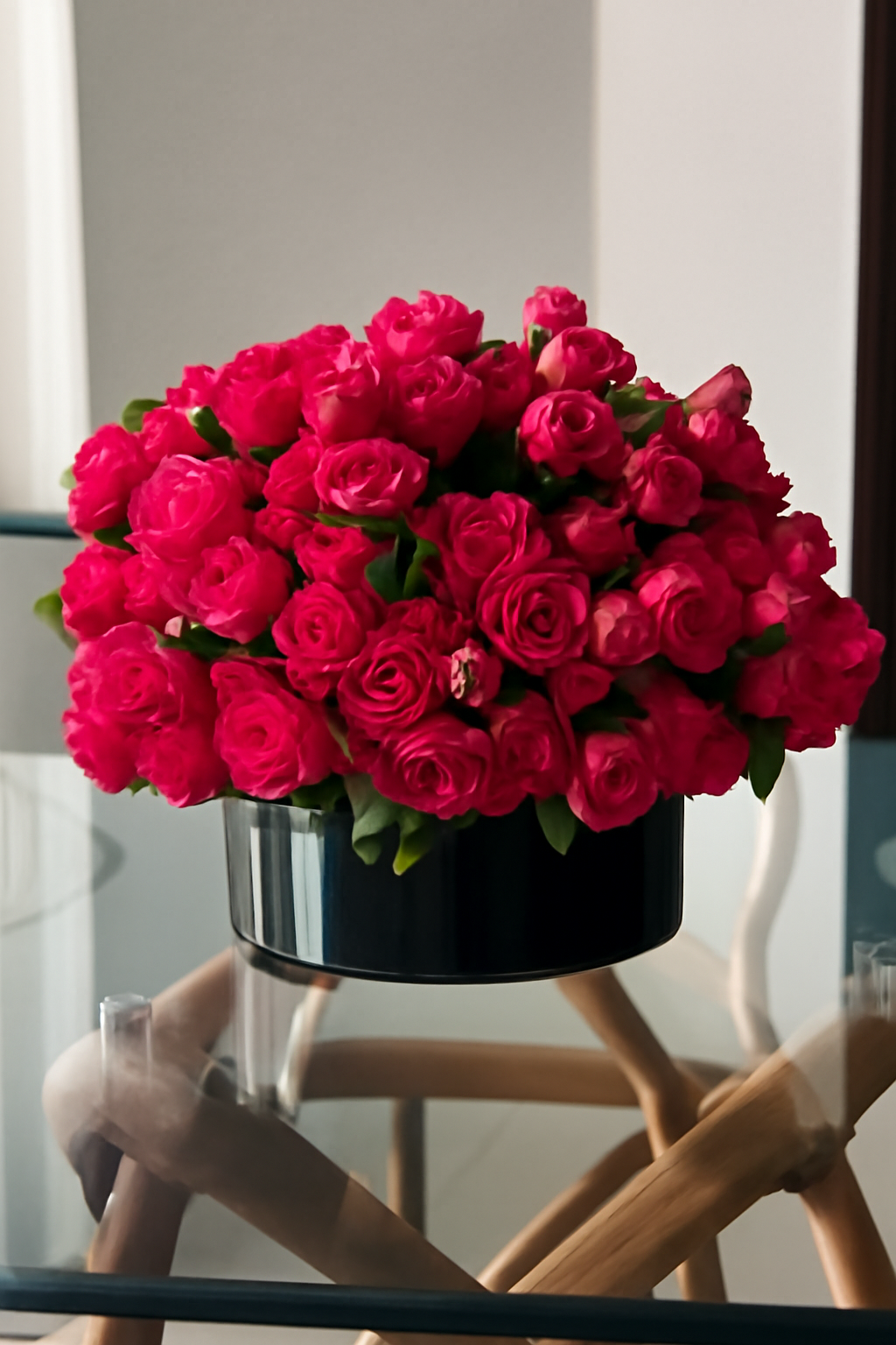 Roses rose foncé dans vase en verre plat noir